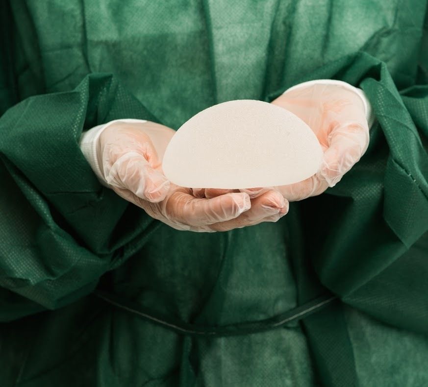 Plastic surgeon hands holding silicon breast implants